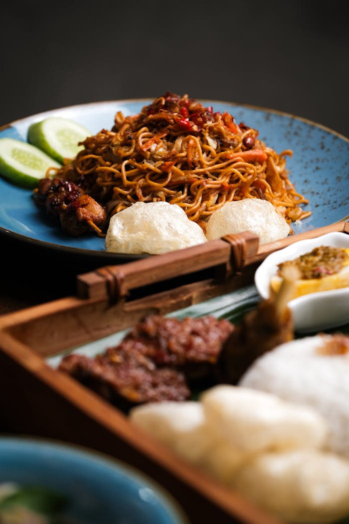 Close-up of flavorful Asian noodles with side dishes on a blue plate, perfect for food enthusiasts.