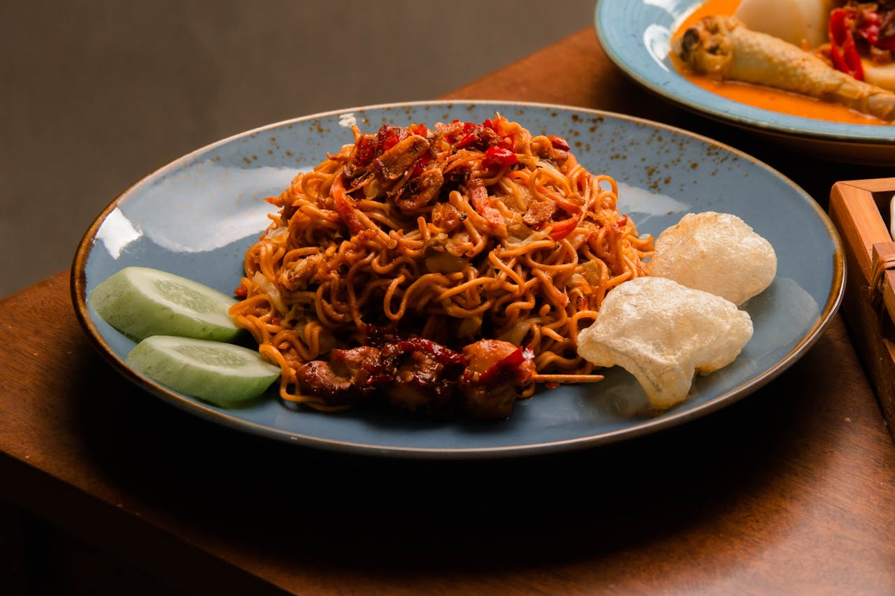 services-01 Plate of savory Asian noodles served with vegetables and crispy snacks.
