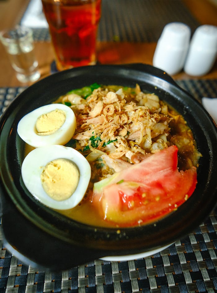 Delicious Indonesian chicken noodle soup with boiled egg and tomato, perfect for a warm hearty meal.